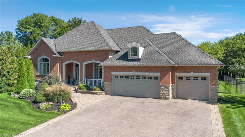 Brick exterior with stone accents, an attached two-car garage, dormer window, and paved driveway
