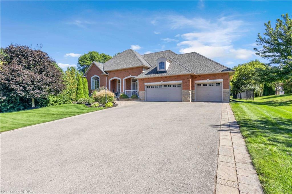 Brick exterior with a stone accent facade, featuring a wide paved driveway and an attached triple garage