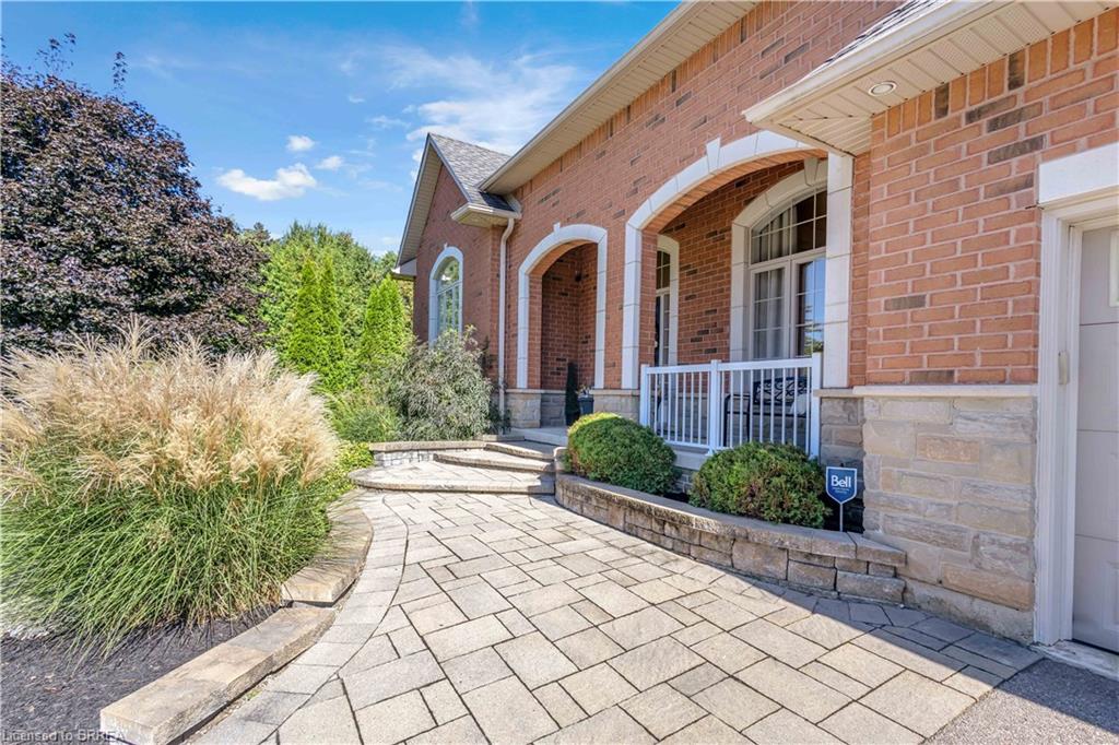 Brick and stone exterior with arched windows, paver walkway, and mature landscaping