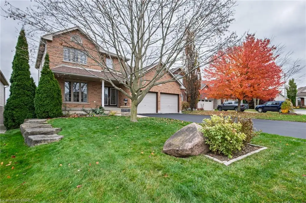 Two-story brick exterior featuring a covered entryway, an attached two-car garage, asphalt driveway, and natural stone hardscaping