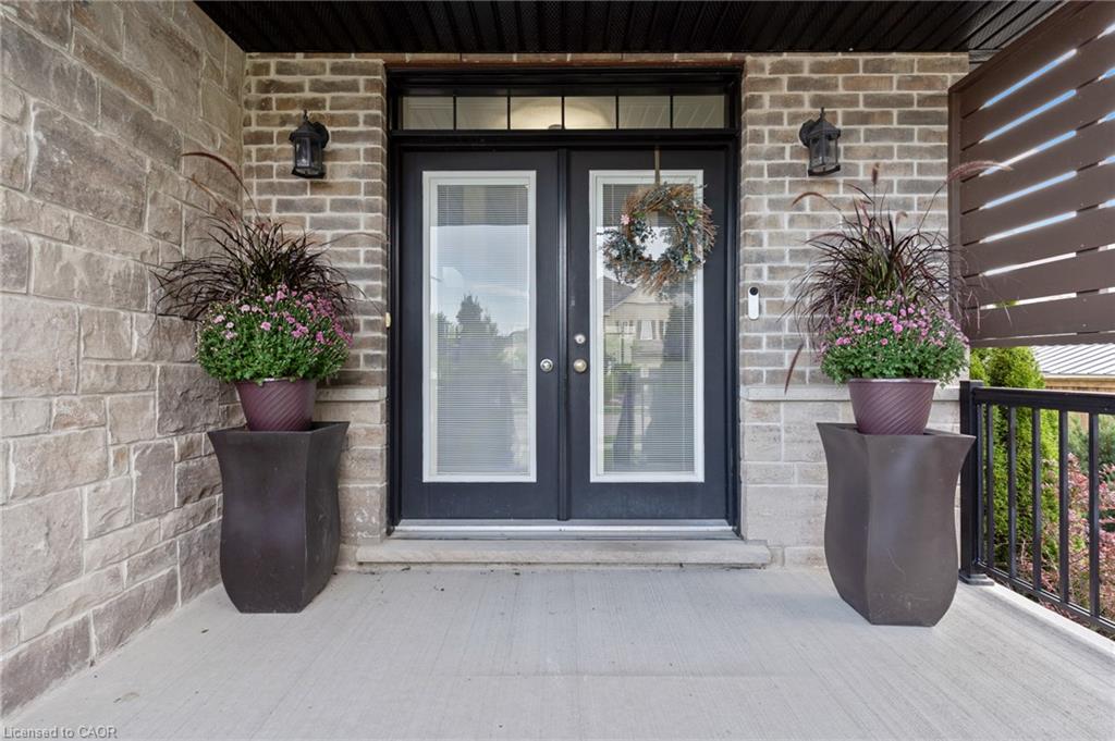 Double entry doors with transoms, brick and stone exterior, and black outdoor sconces