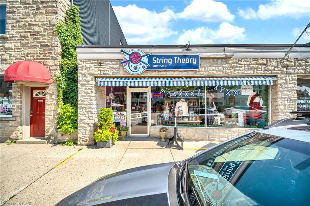 Stone facade storefront with striped awnings and a red entry door with an overhead awning
