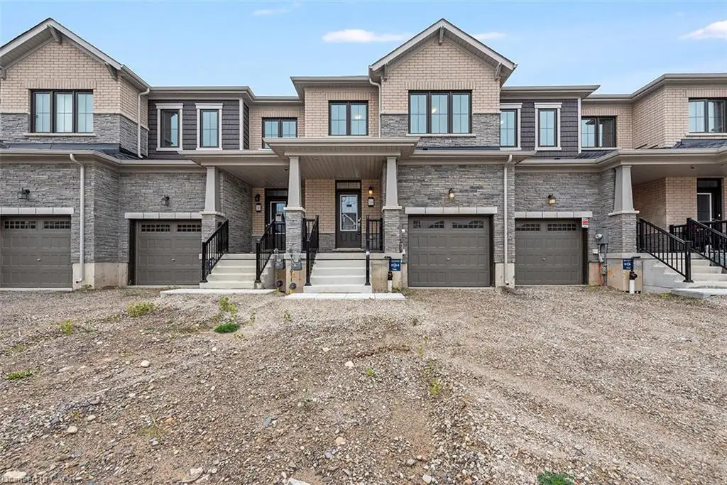 Multi-unit exterior featuring a blend of brick and stone veneer, gabled rooflines, covered entrance porticos with stone-clad columns, and integrated multi-car garage doors