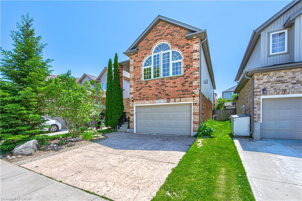 Brick facade with a prominent arched window, integrated garage, and textured concrete driveway