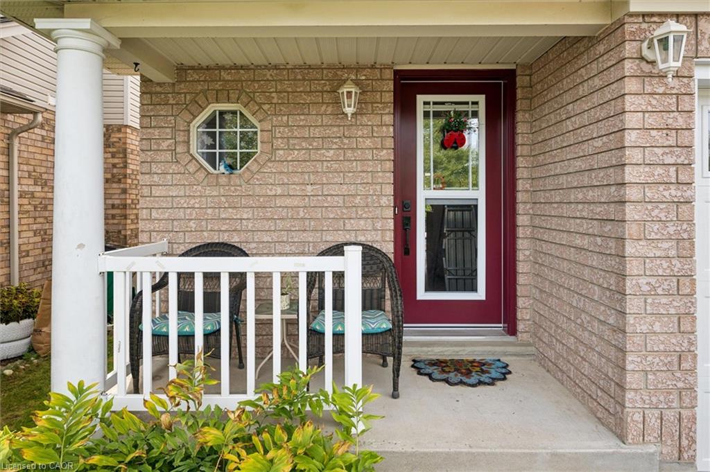 Brick exterior with a covered porch featuring a white column, white railing, and an octagonal window