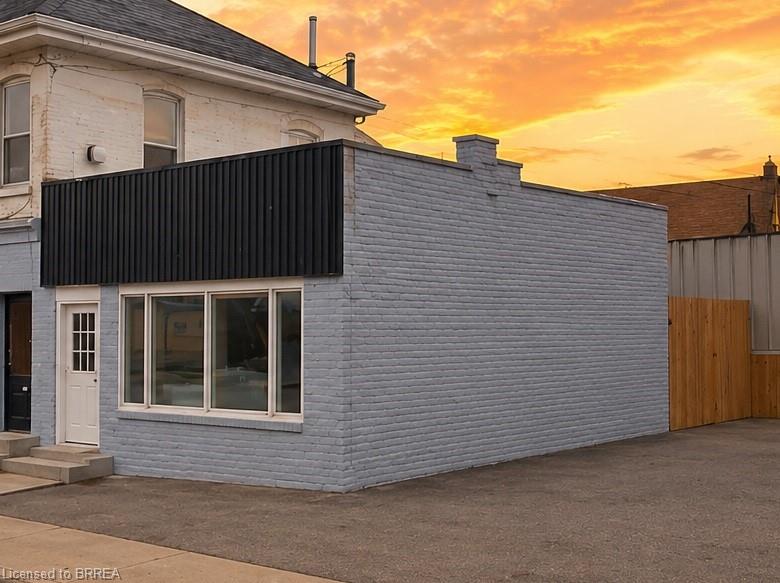 Brick commercial building featuring a large storefront window and a solid wooden fence