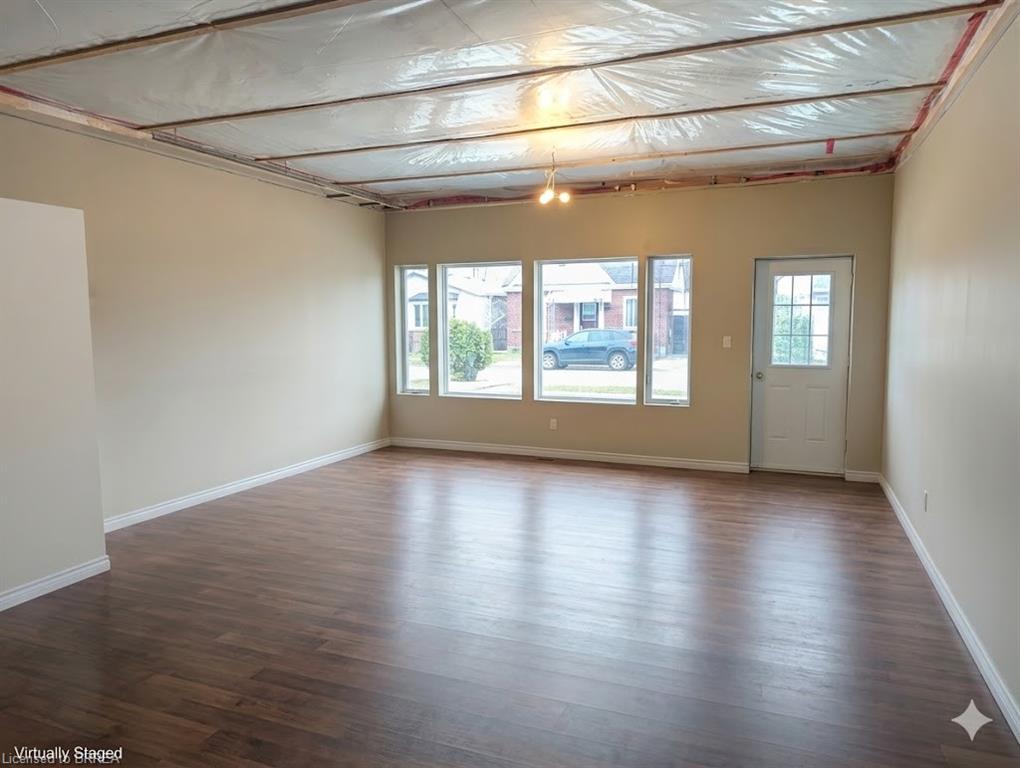 Spacious interior featuring wood-finish flooring, neutral-toned walls, and multiple windows providing natural illumination