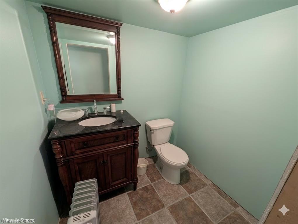Vanity with dark wood-finish cabinetry, a dark countertop, and an undermount sink