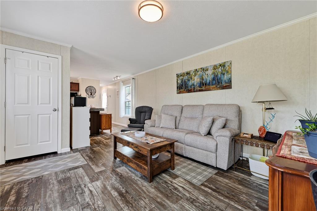 Wood-finish flooring throughout, white paneled interior door, and a kitchen pass-through window