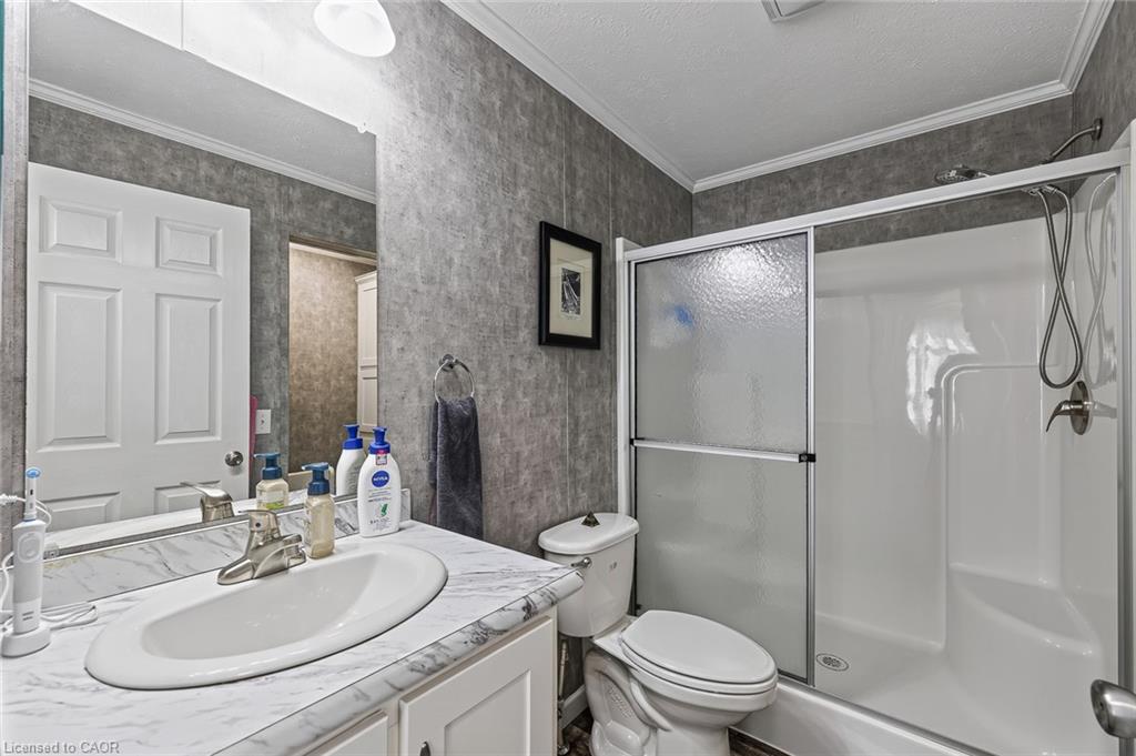 Vanity with a single basin sink and a stone-finish countertop, full-width mirror, and a shower-tub combination with sliding glass doors