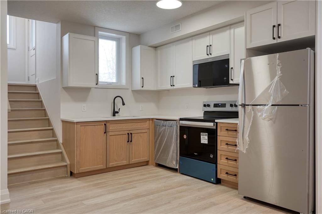 Kitchen with appliances with stainless steel finishes, light countertops, light wood-style floors, and white cabinets