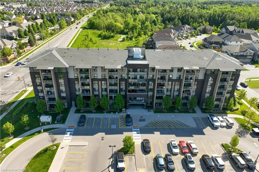 Contemporary multi-story building featuring dark brick and light-colored siding, extensive surface parking, and individual balconies