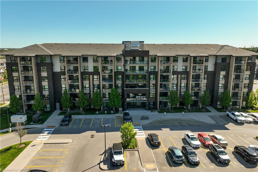 Contemporary multi-story building featuring a dark brick and light-colored façade, multiple private balconies with glass railings, a pitched roof, and a prominent front entrance