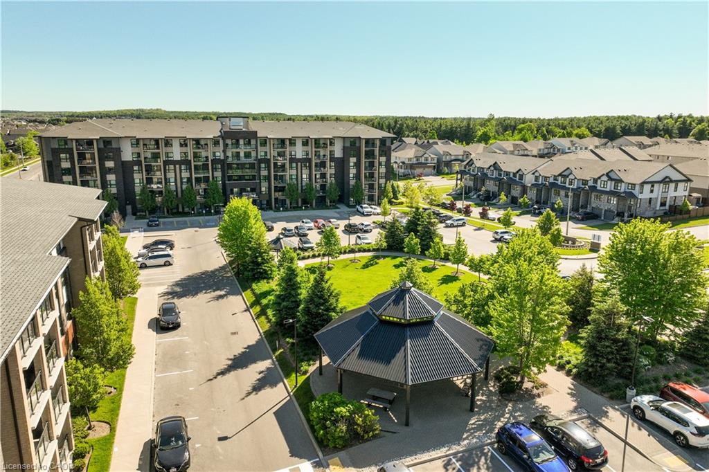 Modern multi-story residential building with balconies, surrounded by paved parking areas and green spaces