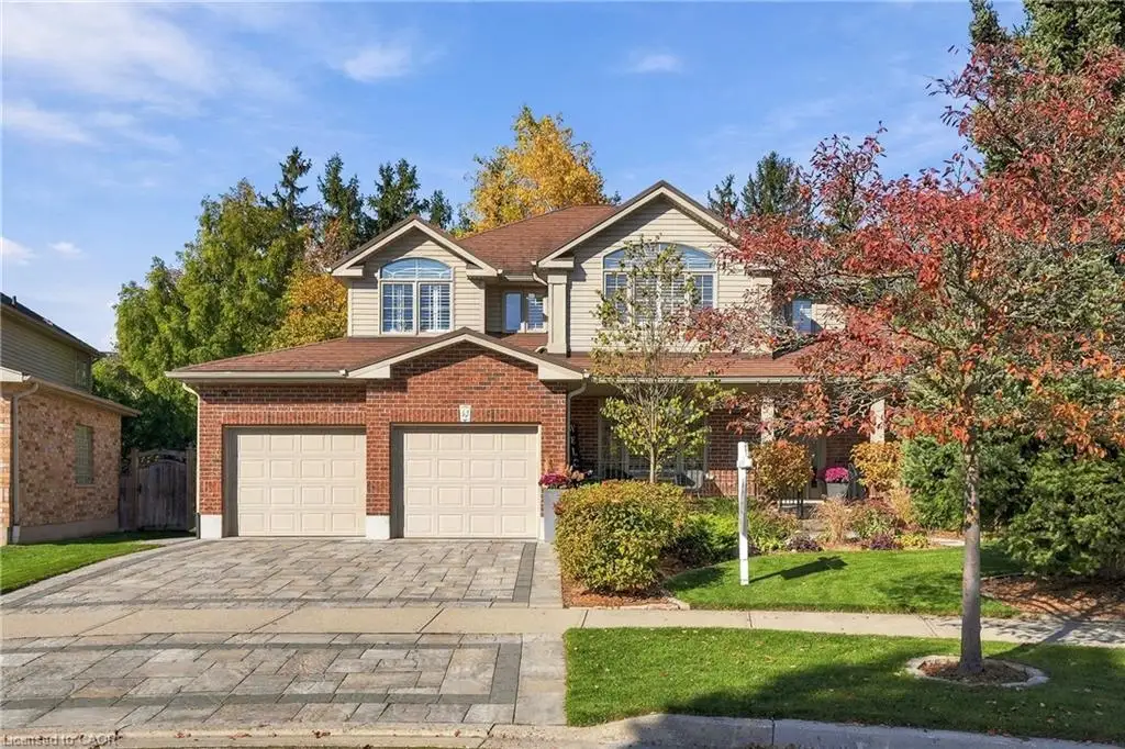 Two-story residence featuring a combination brick and vinyl siding exterior, an attached two-car garage, arched window detailing, and a decorative paver stone driveway