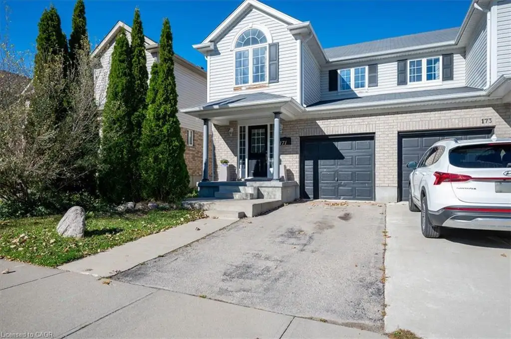Two-story exterior featuring a mix of horizontal siding and brick masonry, arched decorative window, covered front entryway with pillars, and double-car garage
