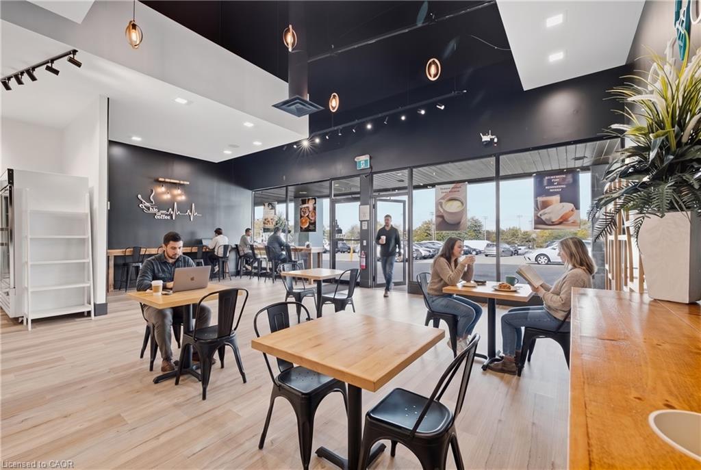 Expansive commercial space featuring light wood-finish flooring, a dark accent wall, track lighting, and a large front window