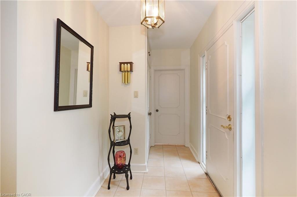 Entryway featuring neutral wall tones, tile flooring, a paneled entry door with brass hardware, and a ceiling-mounted lantern light fixture