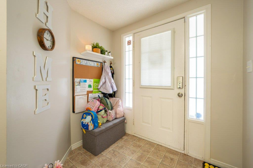Front entry with a white door, frosted glass inset, and side windows, complemented by light-toned wall paint and square tile flooring