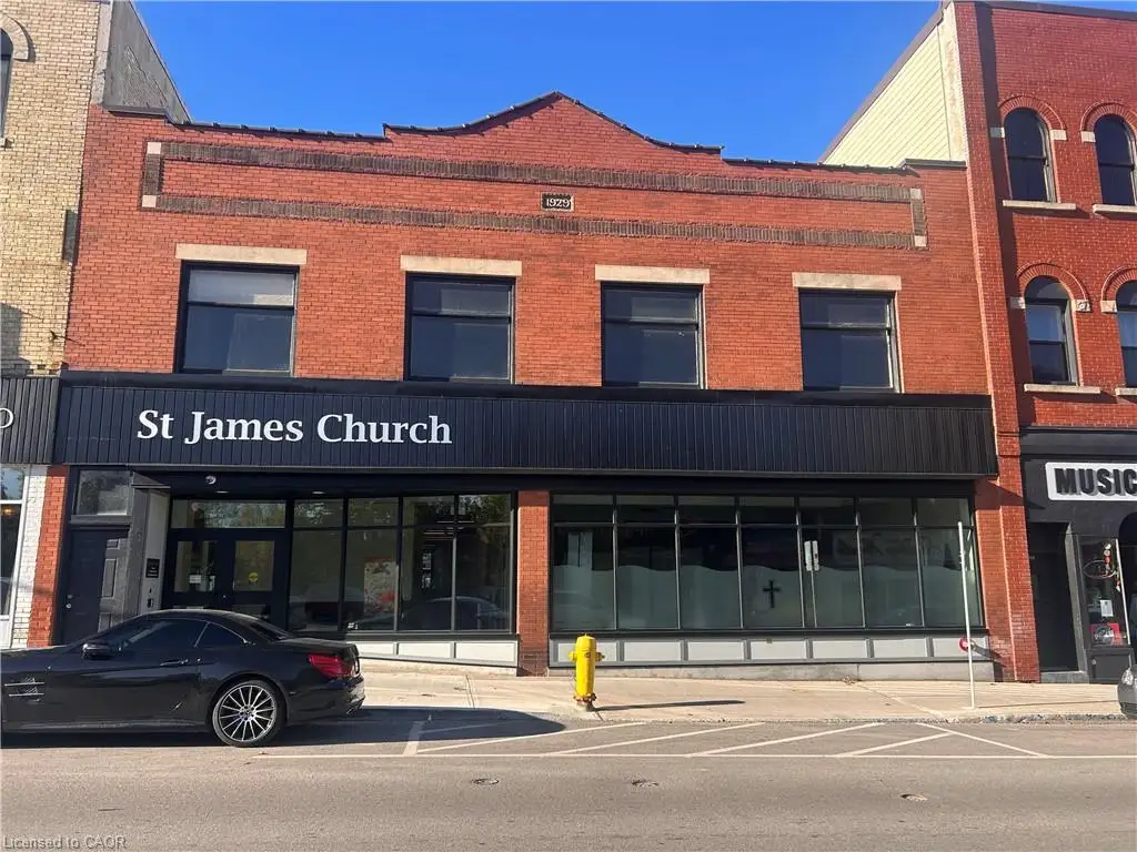Red brick facade featuring a decorative masonry cornice, large multi-pane windows, and a prominent storefront-style ground level with extensive glass glazing