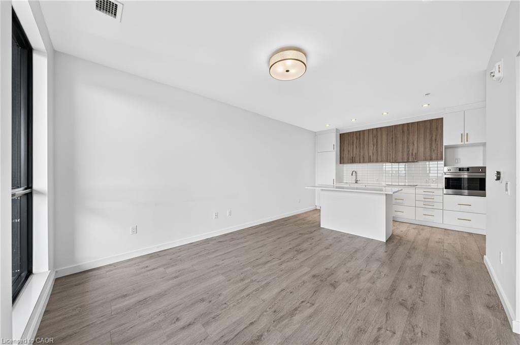 Open-concept living space with wood-finish flooring, white walls, and recessed lighting
