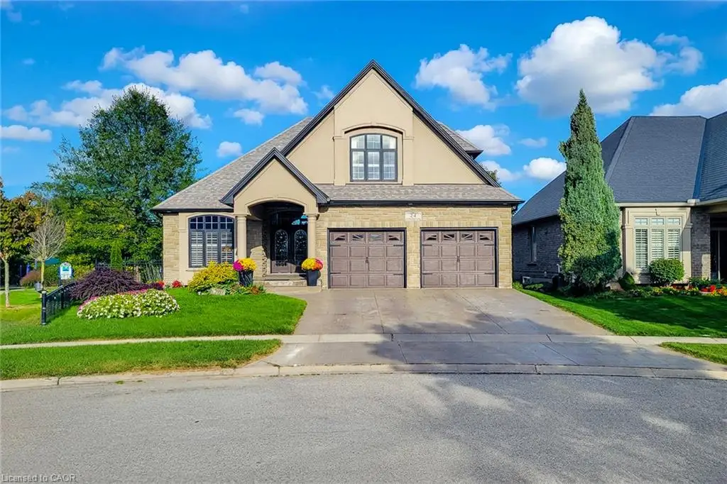 Stone and stucco exterior, arched portico entrance, two-car garage, pitched roofline, and landscaped front yard