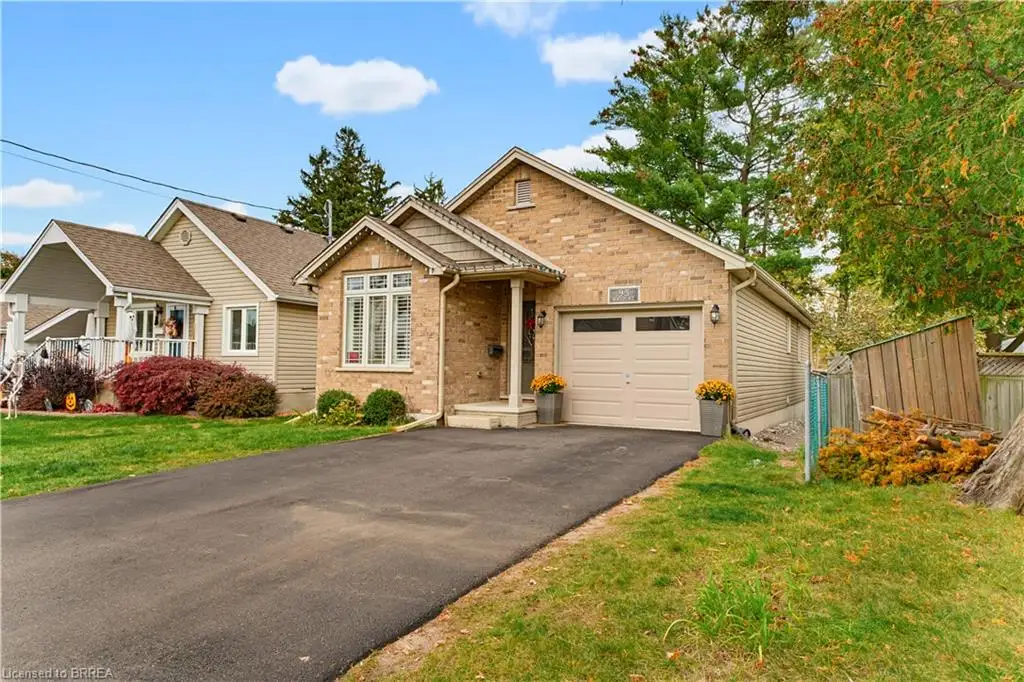 Brick exterior with gable roofline, attached garage, paved driveway, and multi-pane window
