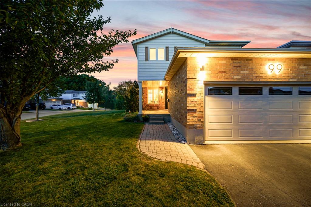Brick and siding exterior with an attached garage, paved driveway, and a paver walkway leading to the front entry