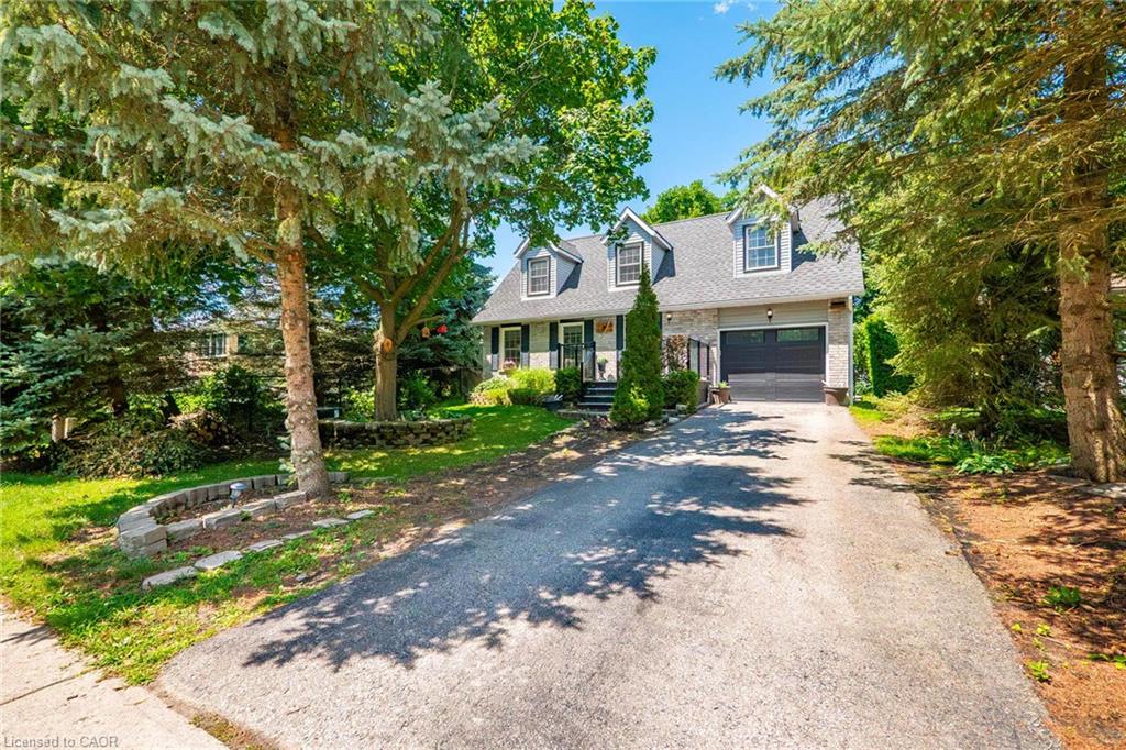 Stone and siding exterior featuring a multi-dormer roofline, an attached garage, and a paved driveway