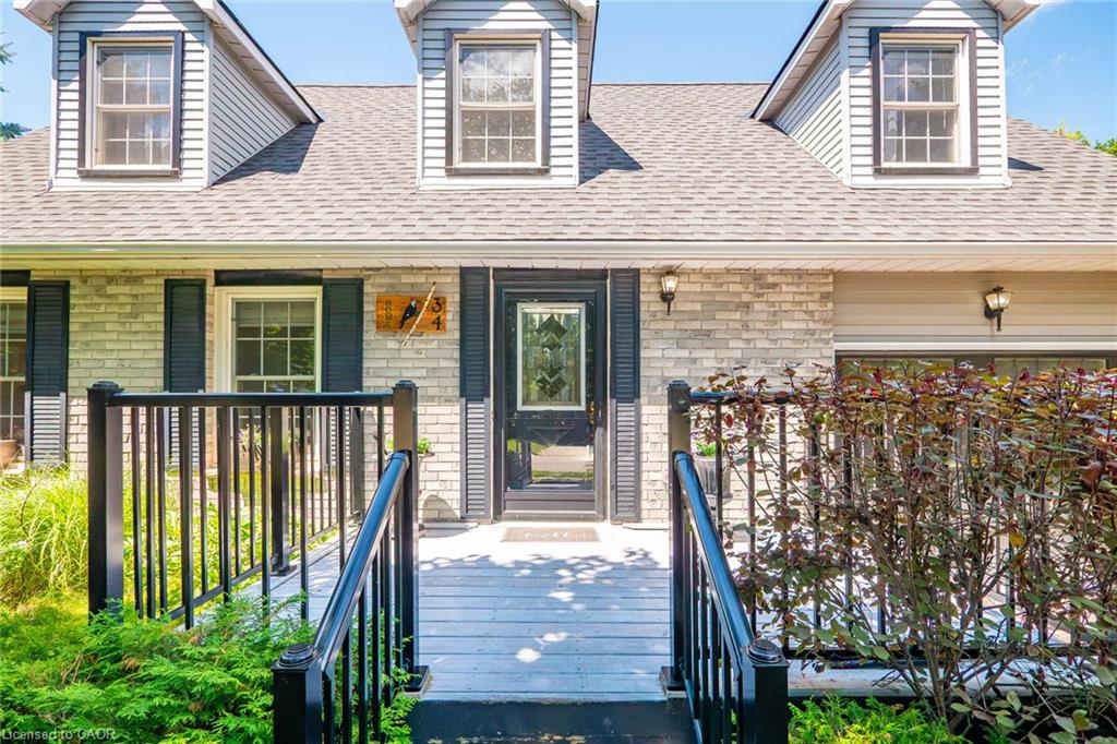 Front exterior featuring light-toned brick, dormer windows, and a black paneled entry door with decorative glass