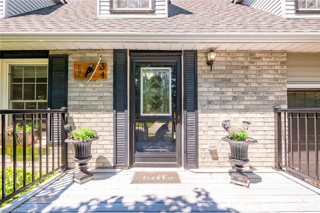 Front entry featuring a full light storm door with decorative glass, flanked by dark shutters and a light brick facade