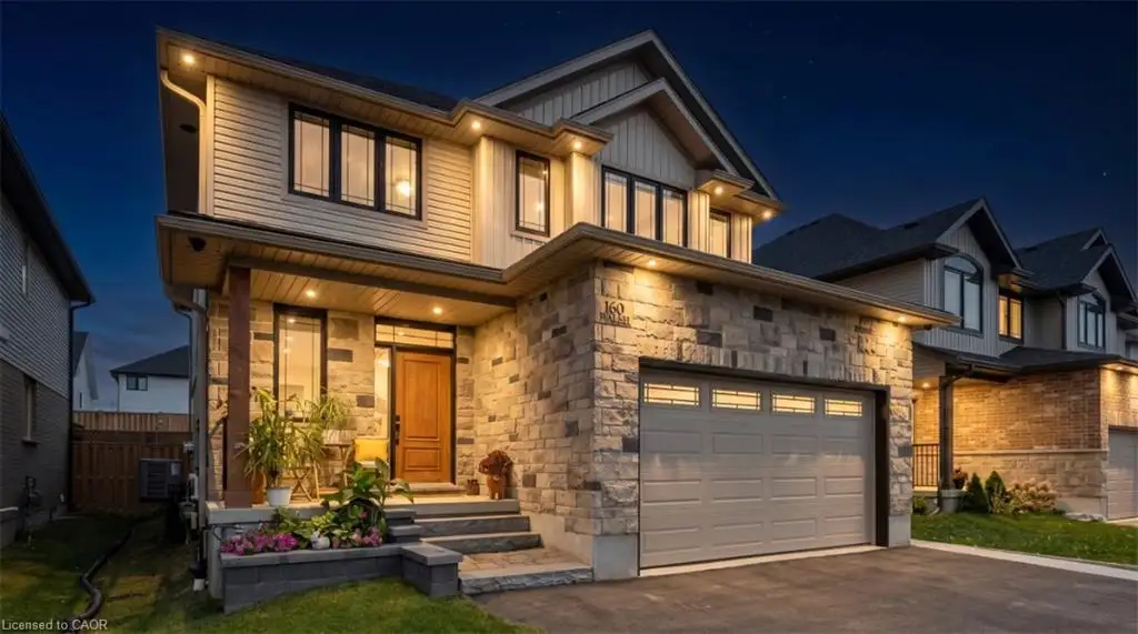 Two-story exterior featuring a stone and siding facade, covered front porch, multi-panel wood door, and multi-car garage