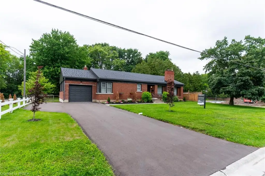 Brick exterior residence featuring a dark shingle roof, attached single-car garage, paved driveway, and white picket fence