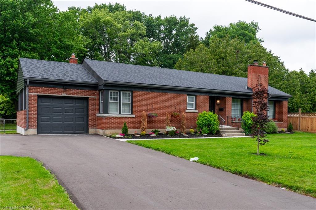 Brick exterior with dark shingle roof and integrated garage