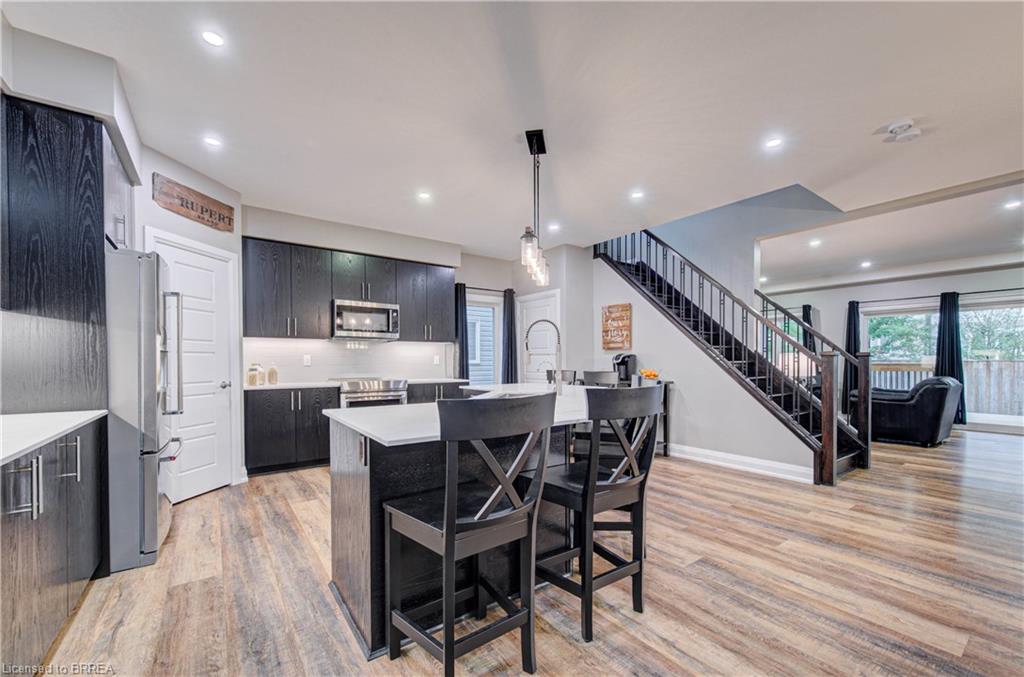 Contemporary kitchen featuring dark wood-finish cabinetry, stainless steel appliances, and an island with a white countertop