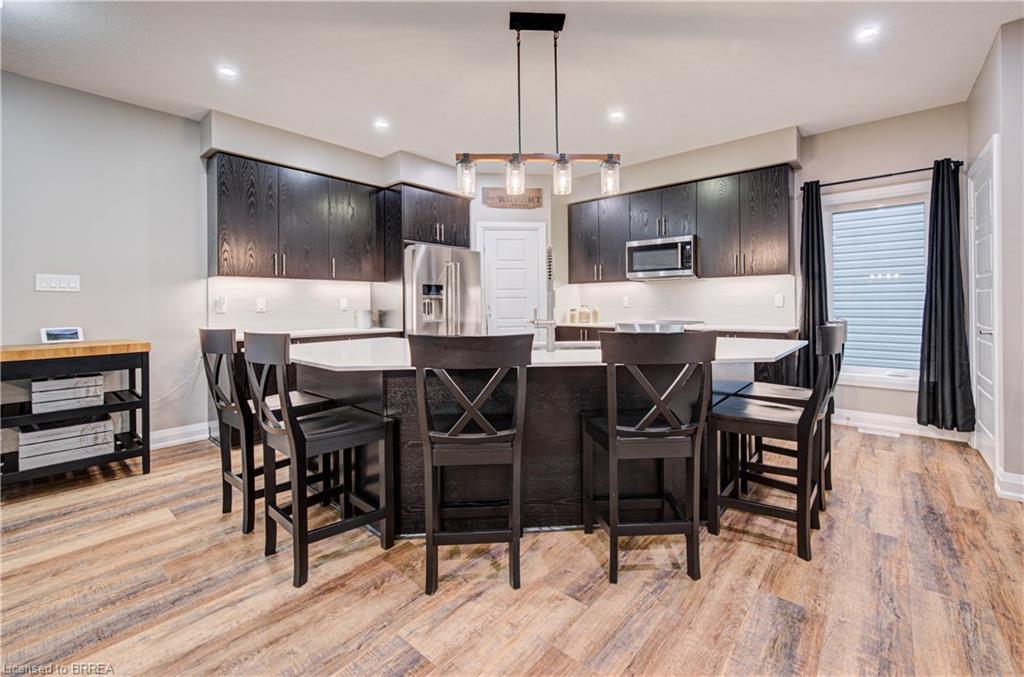 Modern kitchen featuring dark wood-finish cabinetry, stainless steel appliances, a center island with countertop seating, and wood-finish flooring