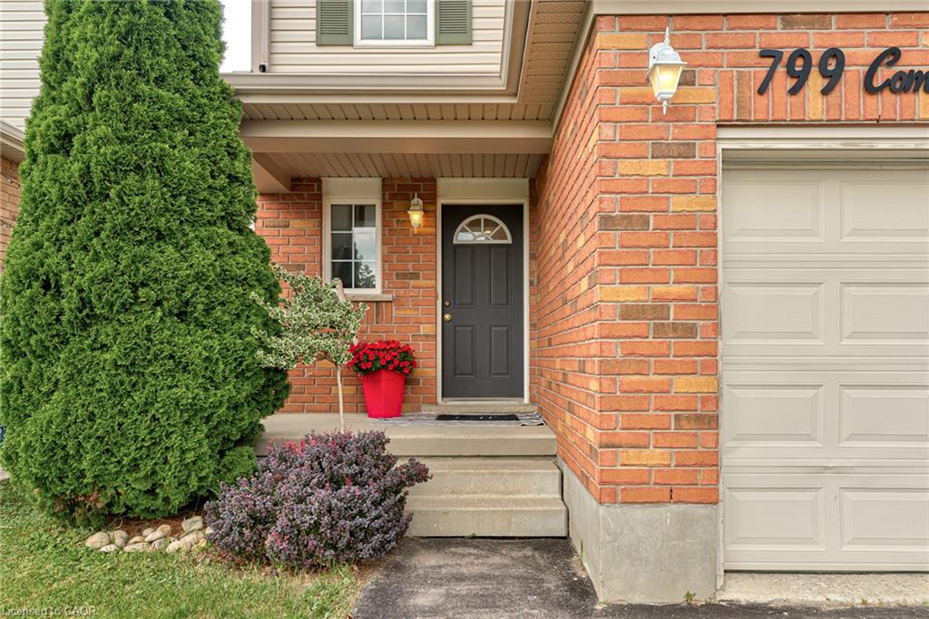 Brick exterior featuring a paneled garage door and dark entry door with an arched window