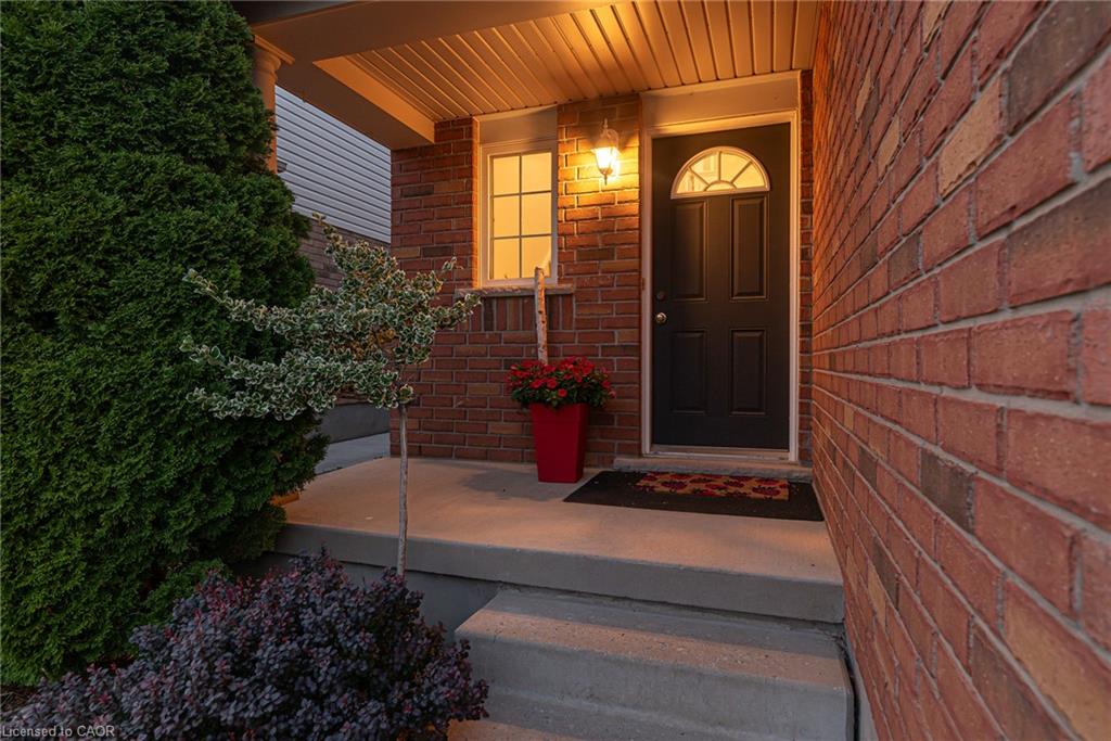 Brick exterior featuring a covered entry, dark panel front door with an arched transom window, exterior wall lantern, and concrete porch