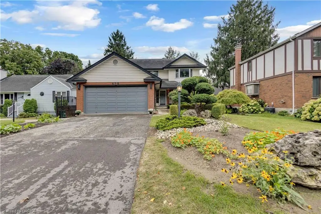 Two-story property with a double garage, brick facade, and decorative front landscaping