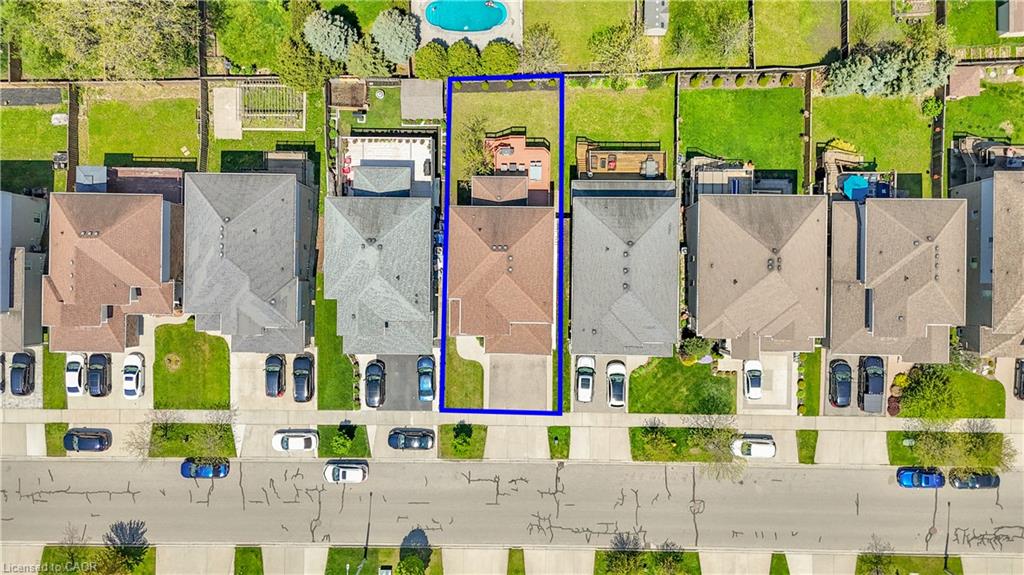 Aerial perspective showcasing the property's rectangular lot, featuring a paved driveway and a green lawn