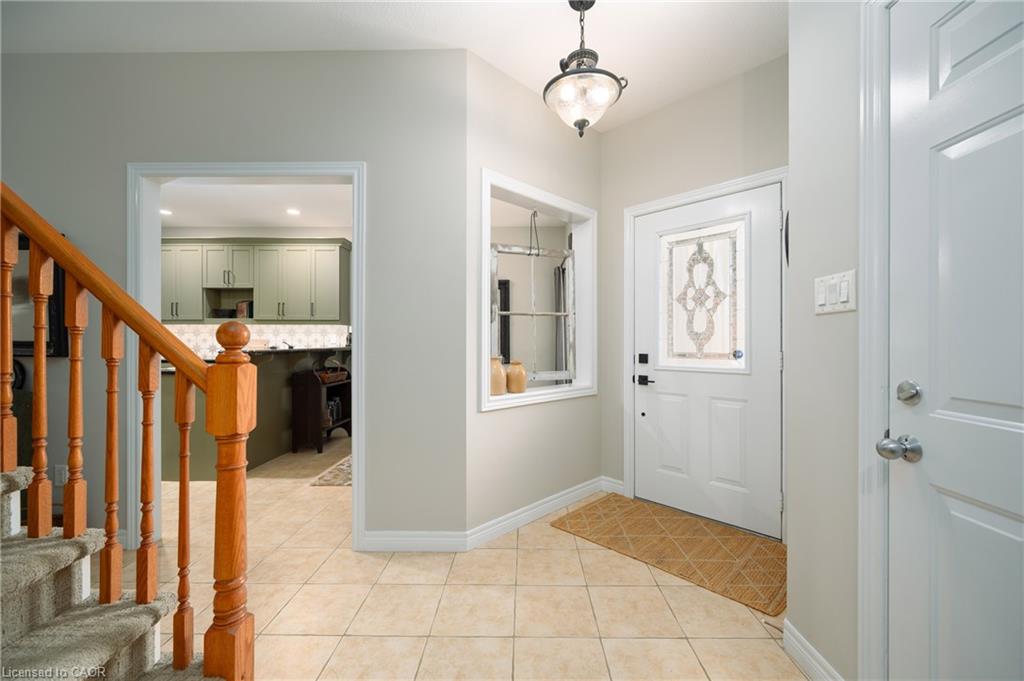 Foyer featuring tiled flooring, a white entry door with decorative glass, a window with a mirrored element, and an overhead light fixture
