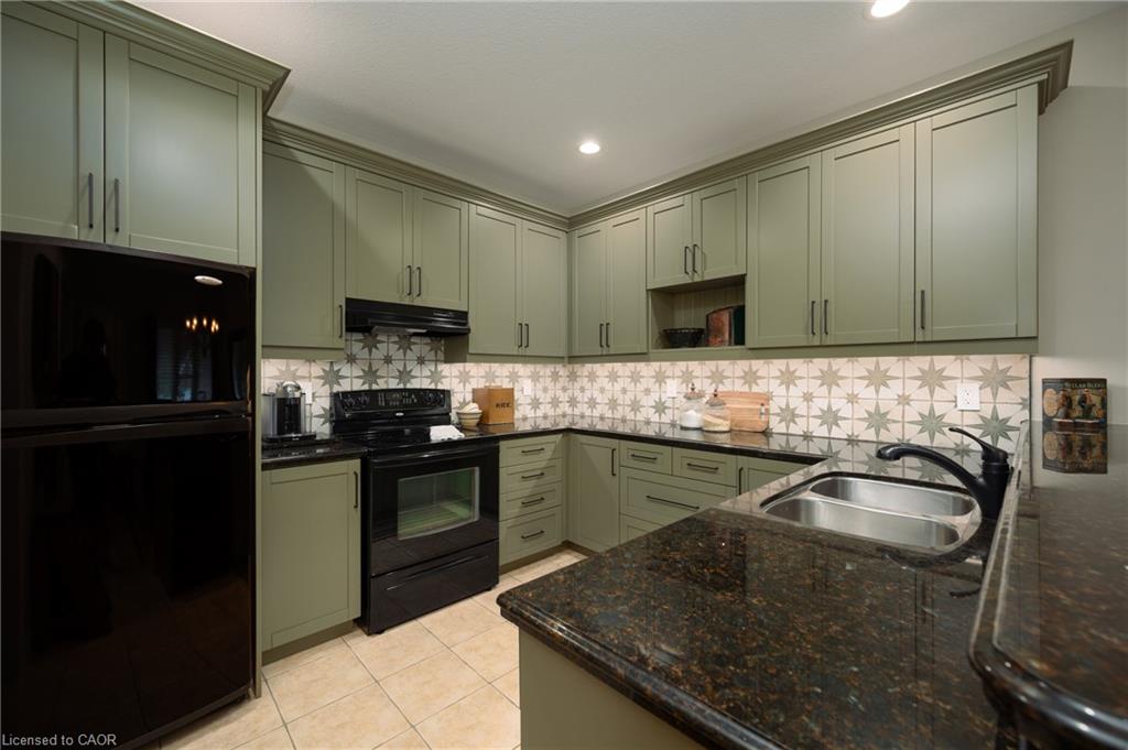 Kitchen featuring shaker-style cabinetry, dark granite countertops, stainless steel double basin sink, and a patterned tile backsplash