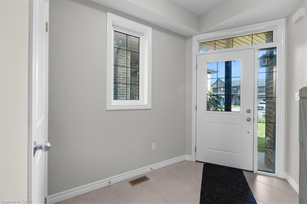Entryway featuring a white paneled door with windowpane detailing, sidelight, transom window, and tile flooring