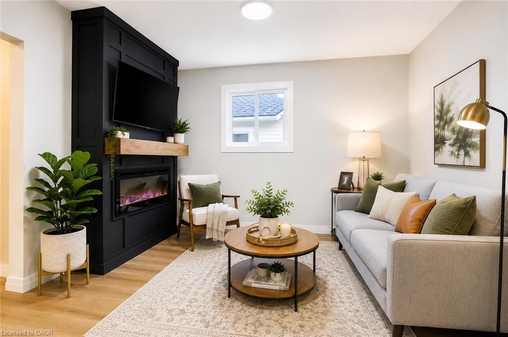 Sophisticated living room showcasing a black fireplace with electric insert, hardwood flooring, recessed ceiling lighting, and large window with natural light
