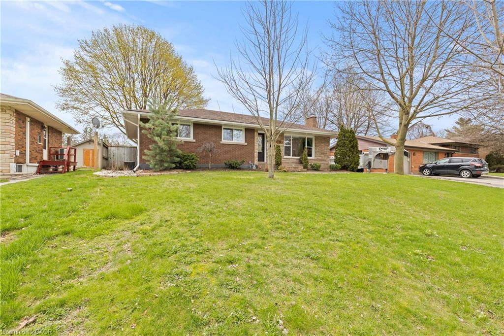 Brick exterior residence featuring a front yard with mature trees
