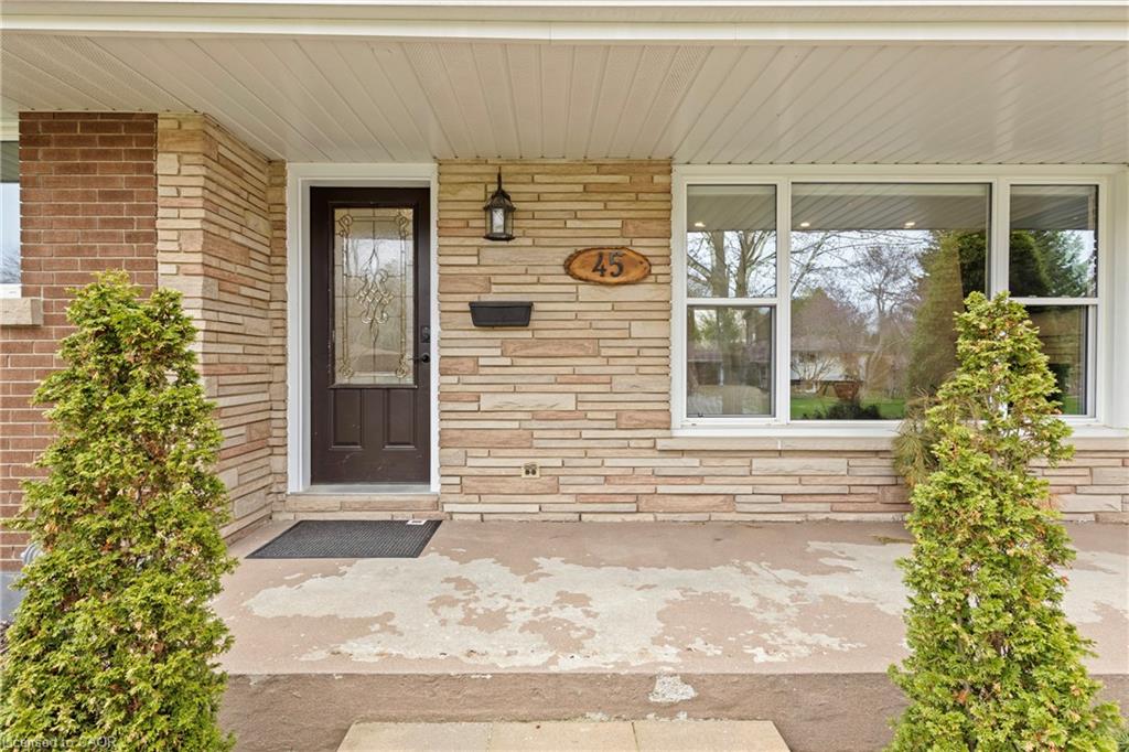 Front facade featuring a dark paneled entry door with decorative glass, stacked stone veneer, and a brick accent wall