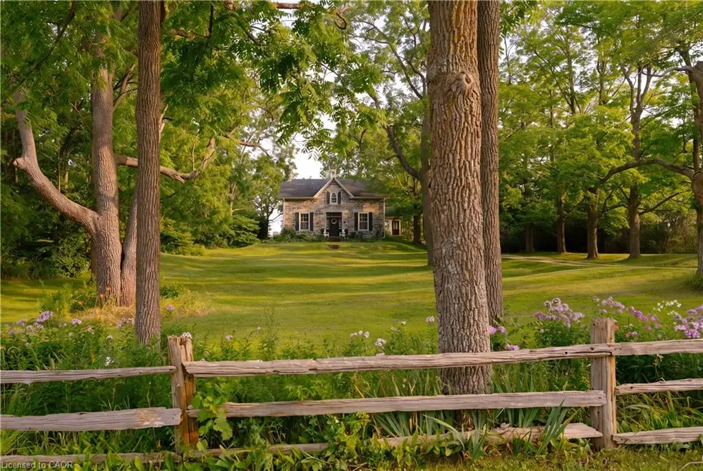 Stone exterior residence with dark shutters and a central front door, set on an expansive manicured lawn