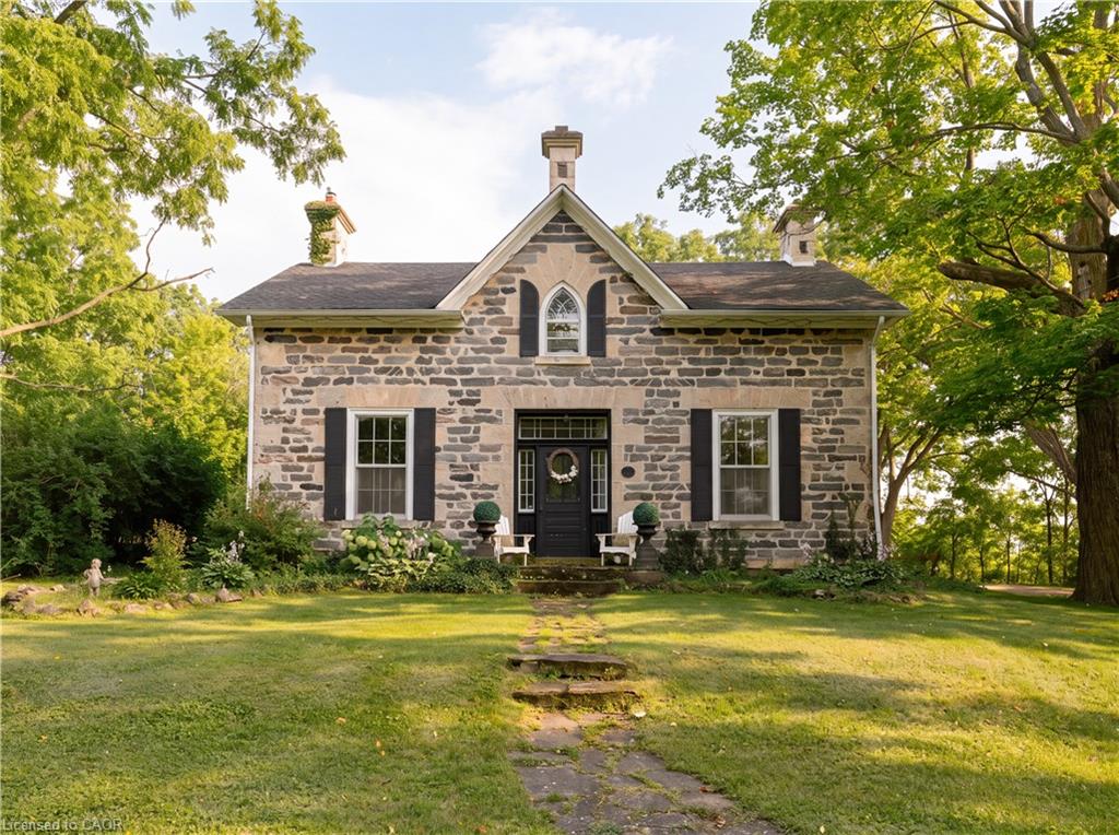 Stone exterior, dark roof, prominent chimneys, arched window, mature trees