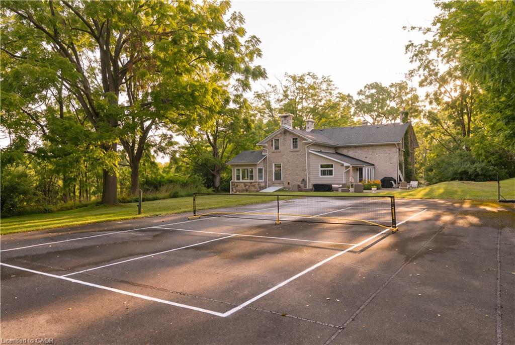 Expansive outdoor court with marked lines and net, surrounded by mature trees