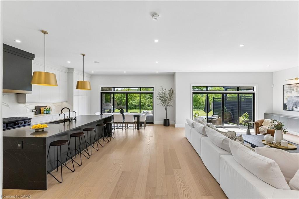 Open-concept living space featuring custom designer kitchen with 10' island clad in quartz countertop with waterfall edge and breakfast bar